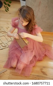 A Girl Playing With Cardboard Toy Dollhouse Furniture.