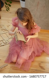 A Girl Playing With Cardboard Toy Dollhouse Furniture.