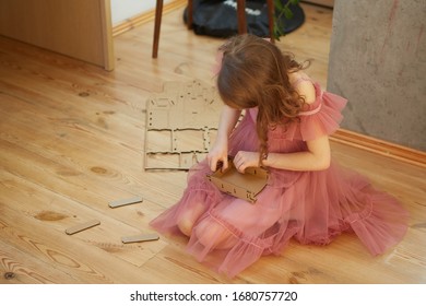 A Girl Playing With Cardboard Toy Dollhouse Furniture.