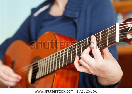 girl playing classical acoustic guitar close up