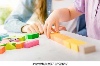 Girl Playing With Colorful Toy Wood Blocks, Her Mother Is Helping Her, Education And Fun Concept