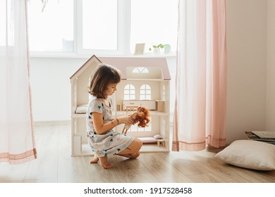 Girl playing with doll house in children room
