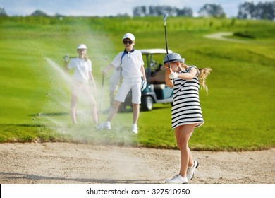 Girl playing golf and  hitting from bunker 