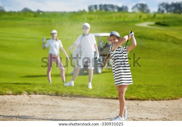 Girl playing golf\
and  hitting from bunker 