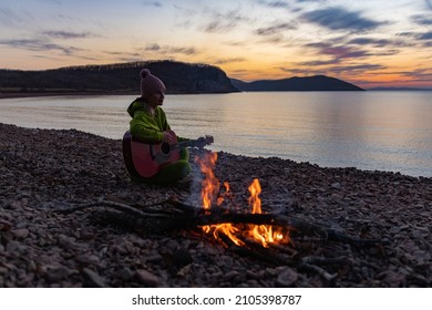 Girl Playing Guitar By The Sea Near The Fire 