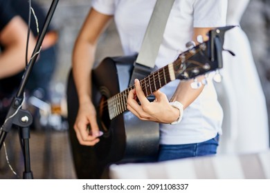 Girl Playing Guitar Close-up On Strings Fingers Black Instrument Concert Jeans T-shirt