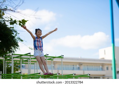 Girl Playing In The Jungle Gym In The Schoolyard