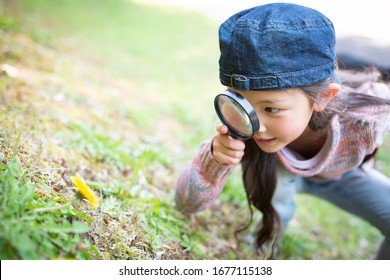 Girl playing with a magnifying glass - Shutterstock ID 1677115138