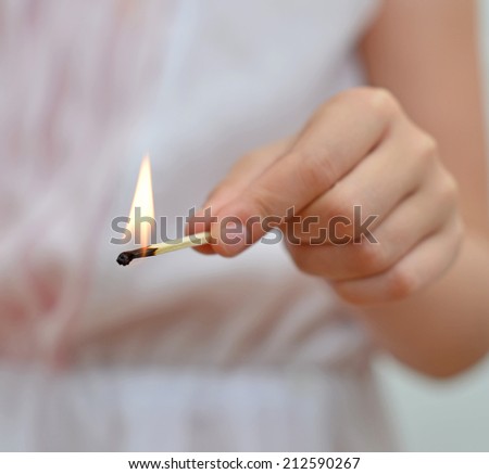 Girl playing with match. Dangerous situation at home.
