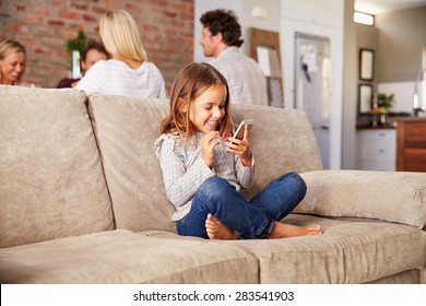 Girl playing with new technology while adults entertain