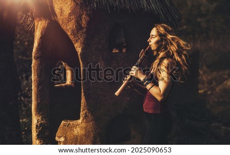 girl playing on shaman flute in the nature.