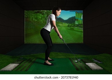 A girl playing screen golf, golf simulator.Young golf player having playing video-game golf indoors.                                                                  