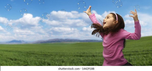 Girl playing with soap bubbles in the field