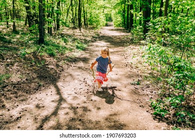 Girl playing with sticks on trail in forest - Oer-Erkenschwick, Germany
