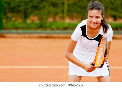 Girl playing tennis at a clay court holding the racket - Powered by Shutterstock