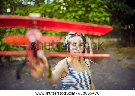 girl playing with toy airplane on street