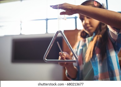 Girl playing triangle in classroom at music school - Powered by Shutterstock