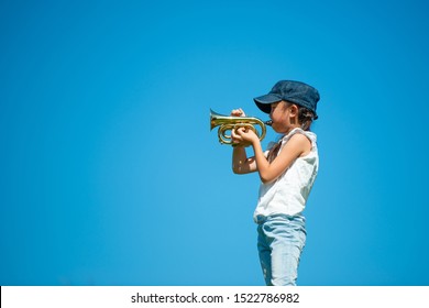 Girl playing trumpet under the blue sky - Shutterstock ID 1522786982