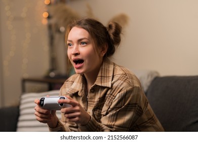 The girl is playing a video game. Joyfully reacts to winning. Fun adventure online games with friends, prizes, win, surprises, virtual reality, cybersport, cyberspace, youth culture.