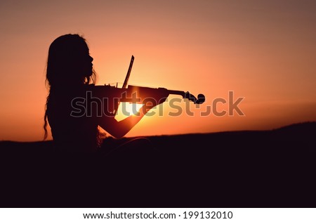 Girl playing the violin in the sunset