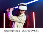 Girl playing virtual reality game in vr headset goggles and lightsaber.