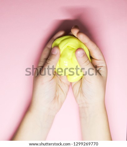 Girl playing with yellow slime in her hands.