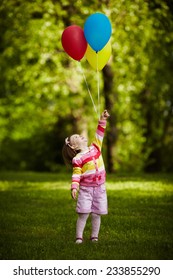 girl plays with balloons in park