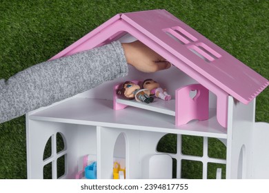 A girl plays with dolls in a dollhouse. Wooden children's toys and furniture.