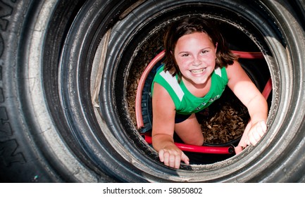 Girl plays in recycled tire tunnel at playground. - Powered by Shutterstock