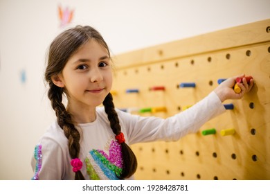 The Girl Plays With Wooden Pegboard With Round Pegs