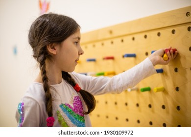 The Girl Plays With Wooden Pegboard With Round Pegs