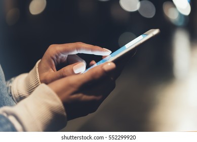 Mädchen, die mit dem Finger auf dem Bildschirm Smartphone auf dem Hintergrund Beleuchtung Bokeh-Farbe Licht in der Nacht atmosphärischen Stadt, Hipster mit in Händen und SMS-Handy, Mock-up Straße, Content Lifestyle
