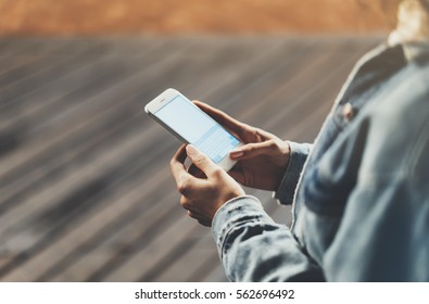 Girl pointing finger on screen smartphone on background wooden floor in night atmospheric city, hipster using in female hands and texting mobile phone, mockup glitter street lifestyle, blured backdrop - Shutterstock ID 562696492