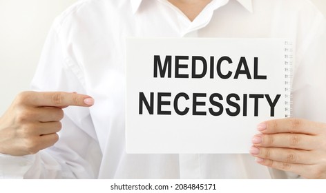 The girl points to a notebook with the text MEDICAL NECESSITY. - Shutterstock ID 2084845171