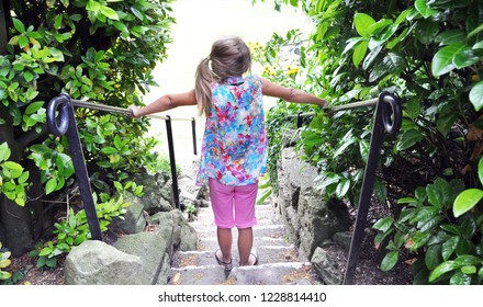 Girl (ponytail)  with colorful clothes standing in a stair outdoor. From the backside. Waiting for something fun during Summer.