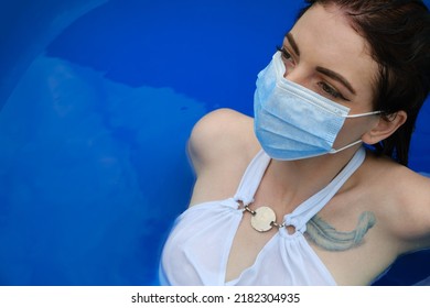 The Girl In The Pool Wears A Protective Mask. Absurd Coronavirus Rules Concept.