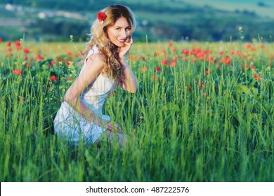 Girl in the poppy field . Happy young woman smiling in the meadow of nature. Beautiful sunset light. Vintage Provence style portrait