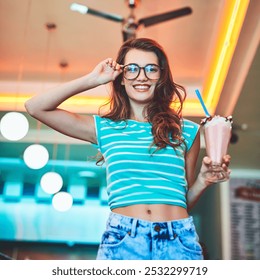 Girl, portrait and smile with milkshake in restaurant for dessert, strawberry drink and sweet treat with glasses. Gen z, person and happy with dairy shake in retro diner for creamy beverage and break - Powered by Shutterstock