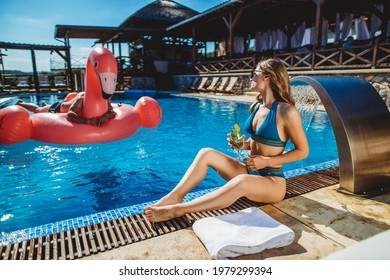 Girl Posing By The Swimming Pool When A Man Approached On A Pink Flamingo Stock Photo.