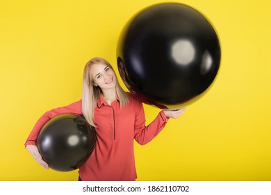 Girl Posing With Two Giant Balloons On A Yellow Background