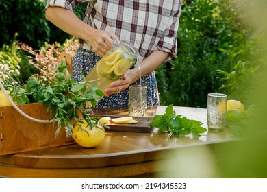 Girl pouring homemade lemonade drink or infused lemon water in summer garden back yard. - Powered by Shutterstock