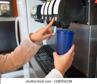 Girl Pours A Fizzy Drink Into A Blue Glass From A Vending Machine