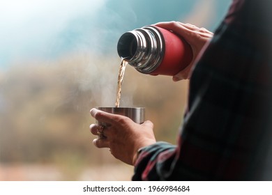 A girl pours tea from a thermos against a background of mountains
 - Powered by Shutterstock