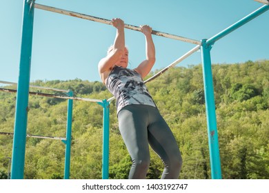 Girl practicing in the morning in the park. Bright sunlight. Strength practice with metal bars. Fitness, healthy lifestyle - Shutterstock ID 1403192747
