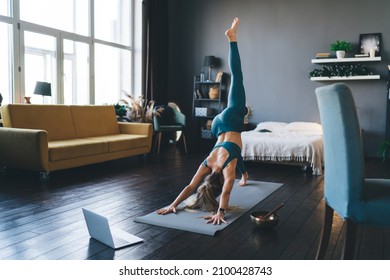 Girl practicing yoga on fitness mat at home. Concept of healthy lifestyle. Athletic woman in sportswear and barefoot. Interior of studio apartment at sunny day
