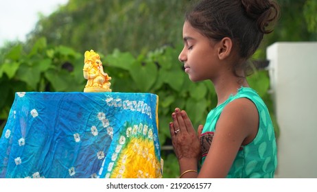 Girl Praying With Eyes Closed And Folded Hands In Front Of An Idol Of Lord Ganesha During Ganesha Or Vinayaka Chaturthi Festival Celebrations At Home - Delhi, India, August, 2022