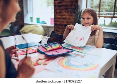 Girl presenting her artwork teacher  Woman assisting schoolgirl during classes at primary school  Child drawing picture sitting at desk in classroom  Girl drawing pictures  Back to school