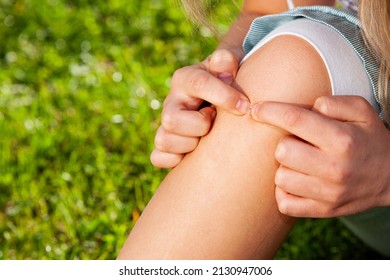 Girl presses on a splinter on her shinbone