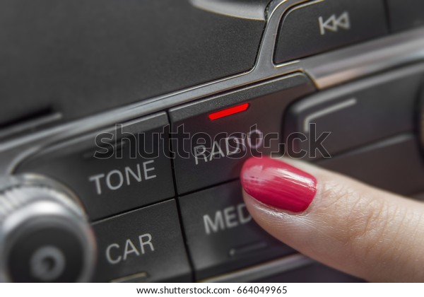 Girl pressing car radio stereo panel and\
modern dashboard electric equipment\
close