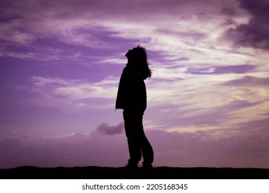 A Girl In Profile Stands At A Purple Sunset On The Shore